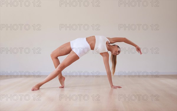 Flexible woman is training in a light studio. The concept of gymnastics