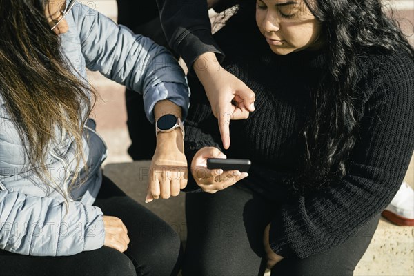 Happy friends sharing multimedia content online with their smartphones and smartwatch