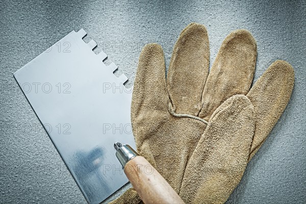 Bricklaying trowel working gloves on concrete background construction concept