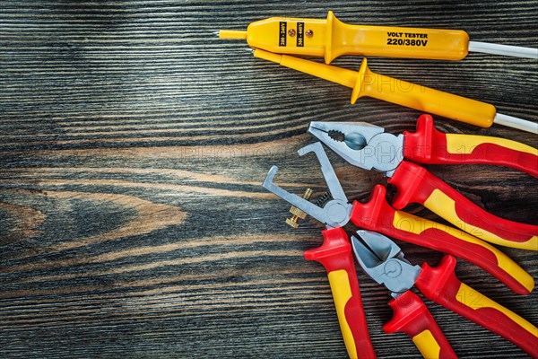 Electrical tester insulated wire strippers cutting nippers pliers on wooden board electricity concept