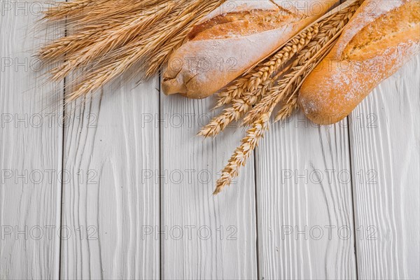 Baguettes and ears of wheat rye on vintage wooden painted boards food and drink concept