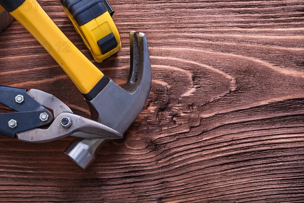 Claw hammer pliers and tape measure on wooden panel construction concept