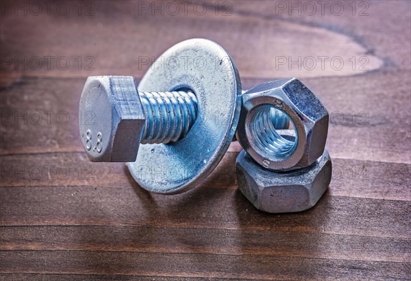 Collection of metal screw nut and bolt washers on vintage wooden board maintenance concept