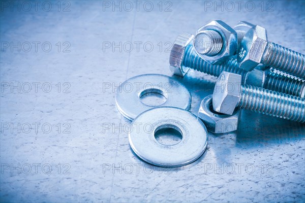 Metal threaded bolts nuts and bolts washers on metallic background copy space image construction concept