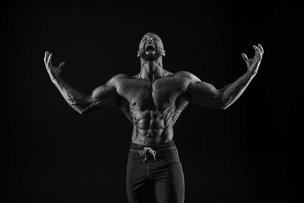 Silhouette of a strong bodybuilder. Confident young fitness athlete with a powerful body and perfect abs. Black and white photography. Dramatic light. Mixed media