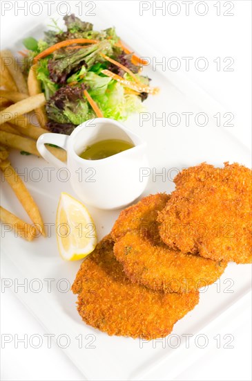 Classic breaded Milanese veal cutlets with french fries and vegetables on background