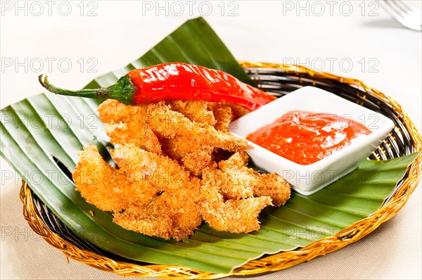 Fresh deep fried buffalo shrimps with a red chili pepper on top and sweet and sour sauce dip on side