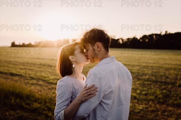 Couple in love in a field at sunset on a date in summer. Wedding engagement of a young couple