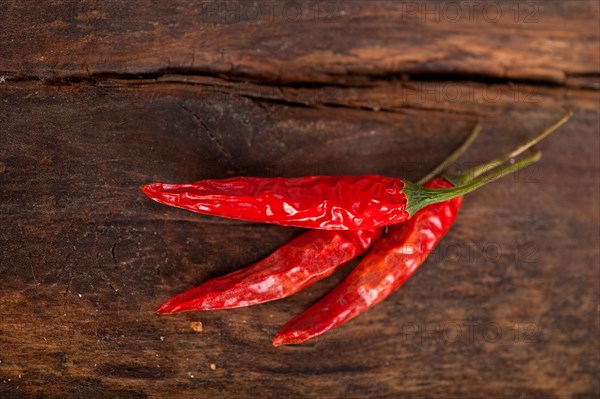 Dry red chili peppers over old wood table