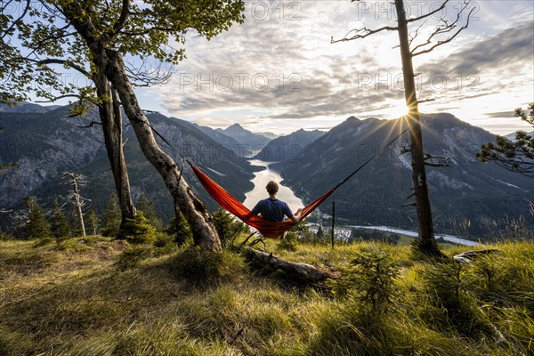 Young man sitting in an orange hammock