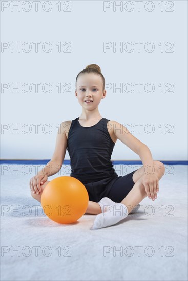 Image of a little girl with a ball in the gym. Gymnastics concept. Mixed media