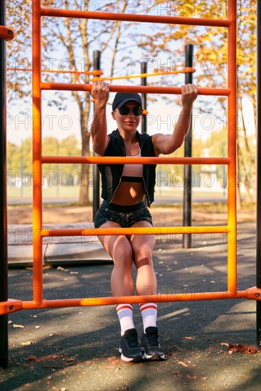 Beautiful young fitness girl is warming up at the stadium before training. Attractive slender brunette in a tracksuit