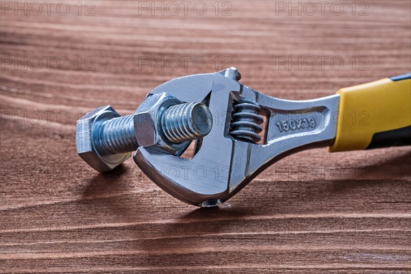 Adjustable spanner and nut on wooden board Construction concept