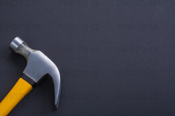 Claw hammer with yellow handle on black background
