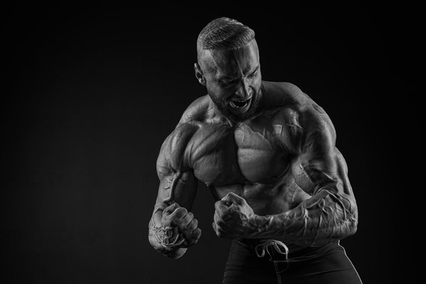 Silhouette of a strong bodybuilder. Confident young fitness athlete with a powerful body and perfect abs. Black and white photography. Dramatic light. Mixed media