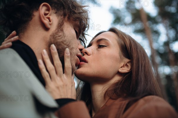 Romantic couple of lovers kisses on a date in the park in cold weather. Fashionable couple in coat