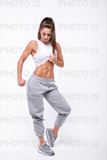 Young white fitness woman wearing sportswear standing over white wall background. Fitness concept. Mixed media