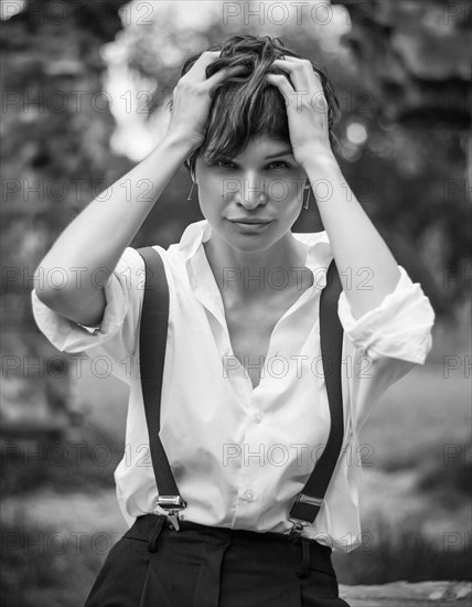 Image of a stylish beautiful woman in a park against the background of a destroyed building. The concept of style and fashion