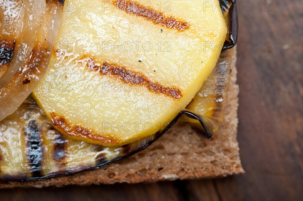 Grilled vegetables on rustic bread over wood table