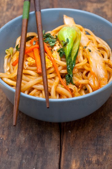 Hand pulled stretched Chinese ramen noodles on a bowl with chopstick