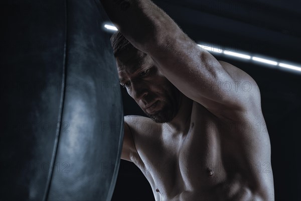 The kickboxer was very tired and hung on the punching bag. Sports training. The concept of mixed martial arts. MMA