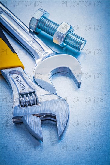 Adjustable spanner open-end wrench bolt and nut on metallic background construction concept