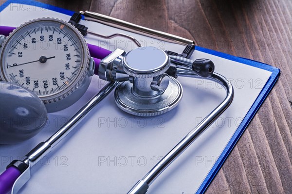 Blood pressure monitor and stethoscope on clipboard with blank sheet medical concept