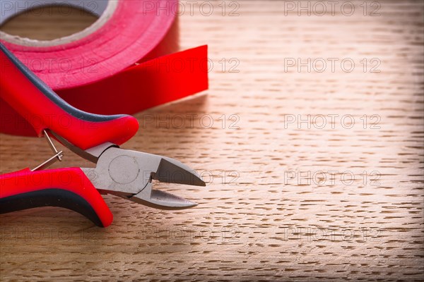 Tongs with insulating tape on wooden board