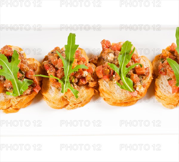 Fresh tipycal italian bruschetta with tomato and arugula on top