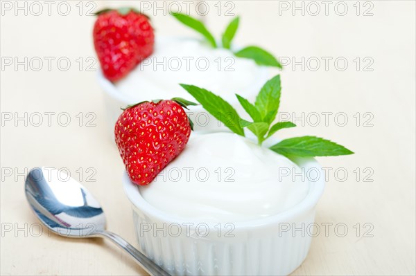 Organic Greek yogurt and strawberry over white rustic wood table