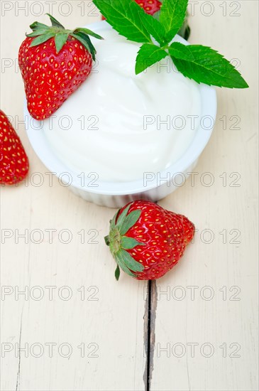 Organic Greek yogurt and strawberry over white rustic wood table