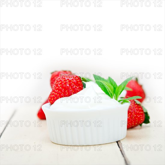 Organic Greek yogurt and strawberry over white rustic wood table