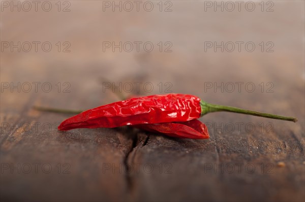 Dry red chili peppers over old wood table