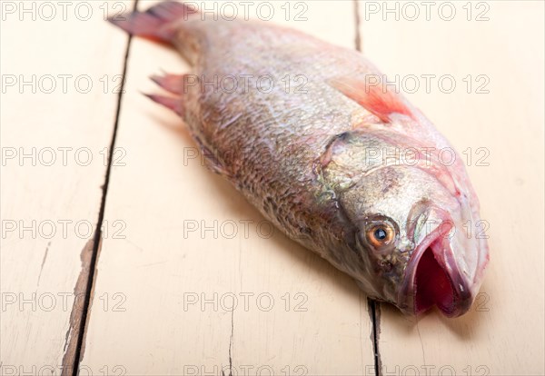 Fresh whole raw fish on a wooden table ready to cook