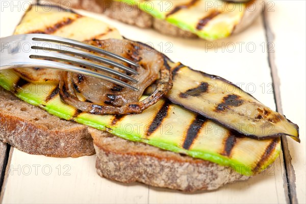 Grilled vegetables on rustic bread over wood table