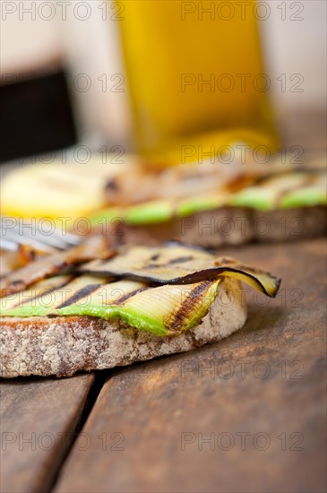 Grilled vegetables on rustic bread over wood table