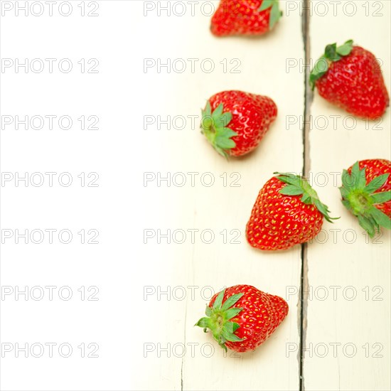 Fresh organic strawberry over white rustic wood table