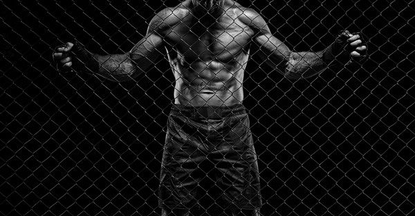 Black and white image of a man in a boxing cage. The concept of sports