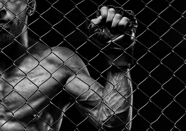 Black and white image of a man in a boxing cage. The concept of sports