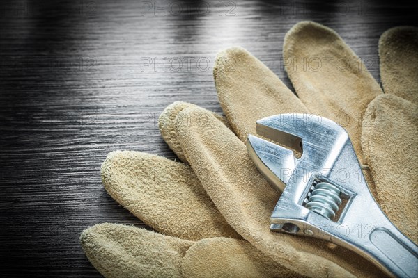 Adjustable wrench protective gloves on wooden board