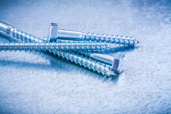 Horizontal version of metal screw bolts on a metallic background Design concept