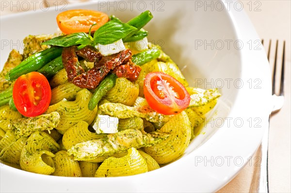 Fresh lumaconi pasta and pesto sauce with vegetables and sundried tomatoes