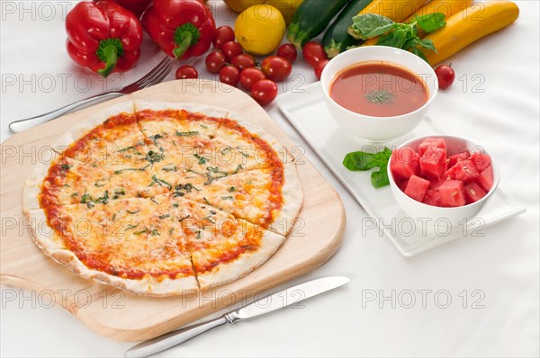 Italian original thin crust pizza Margherita with gazpacho soup and watermelon on side