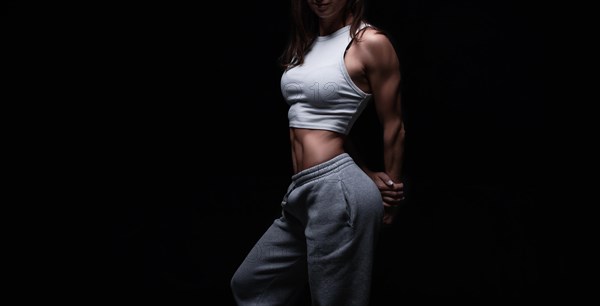 Athletic fitness woman posing in the studio on a dark background. Photo of an attractive woman in fashionable sportswear. Sports and healthy lifestyle. Mixed media