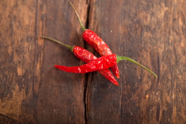 Dry red chili peppers over old wood table