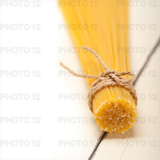 Italian pasta spaghetti tied with a rope on a rustic table