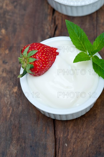 Organic Greek yogurt and strawberry on a rustic wood table