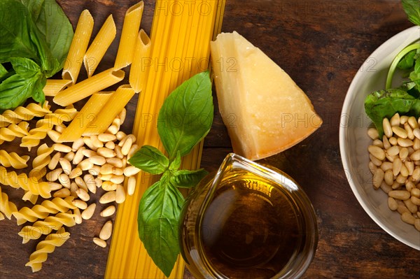 Italian basil pesto ingredients and raw pasta over old wood macro