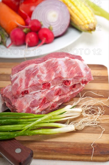 Chopping fresh pork ribs with vegetables and herbs ready to cook