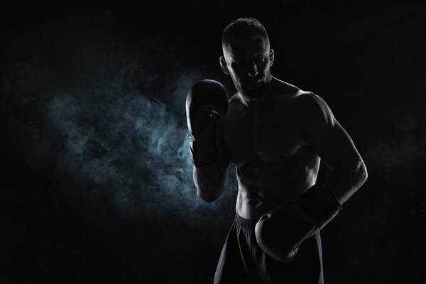 Kickboxer in black gloves posing on a background of smoke. The concept of mixed martial arts. MMA
